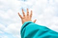 Close up of child hand raised up over blue sky and clouds background. Gesture Royalty Free Stock Photo