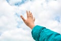 Close up of child hand raised up over blue sky and clouds background. Gesture Royalty Free Stock Photo