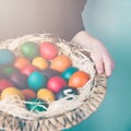 Close up of child hands holding a wicker basket full of colorful Easter eggs. Royalty Free Stock Photo
