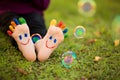 Close up of child human pair of feet painted with smiles outdoor in park with bubble