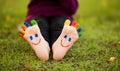 Close up of child human pair of feet painted with smiles outdoor in park