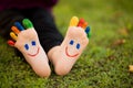 Close up of child human pair of feet painted with smiles outdoor in park