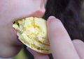 Close up on a child mouth eating sweet yellow macaron
