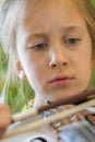 Close up of a child playing violin on green background. Portrait of girl with string and playing violin. Portrait of the little