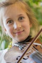 Close up of a child playing violin on green background. Portrait of girl with string and playing violin. Portrait of the little