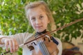 Close up of a child playing violin on green background. Portrait of girl with string and playing violin. Portrait of the little Royalty Free Stock Photo