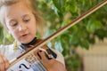 Close up of a child playing violin on green background. Portrait of girl with string and playing violin. Portrait of the little Royalty Free Stock Photo