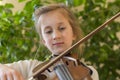 Close up of a child playing violin on green background. Portrait of girl with string and playing violin. Portrait of the little Royalty Free Stock Photo