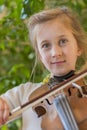 Close up of a child playing violin on green background. Portrait of girl with string and playing violin. Portrait of the little Royalty Free Stock Photo