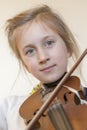 Close up of a child playing violin on isolated light background. Portrait of girl with string and playing violin. Portrait of the