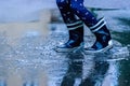 Close up child with rain boots jumping in puddles after rain. Childhood, laisure, happiness concept. Horizontal image Royalty Free Stock Photo