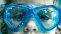 Close-up of a child's face wearing bright blue swimming goggles with water droplets Royalty Free Stock Photo
