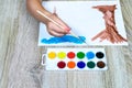 Close-up of a child`s hand with a brush drawing and watercolors. Children`s artist draws, creativity, recreation Royalty Free Stock Photo