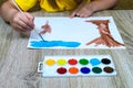 Close-up of a child`s hand with a brush drawing and watercolors. Children`s artist draws, creativity, recreation Royalty Free Stock Photo