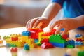 Close-up of child\'s hands assembling vibrant building blocks on a sunlit table