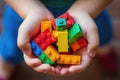 Close-up of a child\'s hands holding colorful building blocks, symbolizing creativity and early development