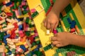 Close up of child`s hands playing with colorful plastic bricks at the table. Early learning. stripe background. Developing toys Royalty Free Stock Photo