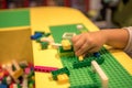 Close up of child`s hands playing with colorful plastic bricks at the table. Early learning. stripe background. Developing toys Royalty Free Stock Photo