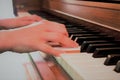 Close up of a child`s hands playing a rustic brown upright piano keyboard