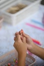 Close-up of a child's hands stringing a red bead onto a thread Royalty Free Stock Photo