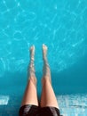 Close-up of a child`s legs sitting on a pool of crystal clear water. Summer vacation, relax Royalty Free Stock Photo