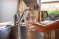 Close up of children hands, pouring glass of fresh water from tap in kitchen Royalty Free Stock Photo