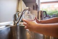 Close up of children hands, pouring glass of fresh water from tap in kitchen Royalty Free Stock Photo