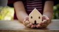 Close up of children`s hand holding wooden house on wooden table, hope for new house, thinking for home Royalty Free Stock Photo