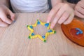 Close-up of children`s hands creating perler bead patterns, make crafts using thermomosaic technique, beading patterns, perler