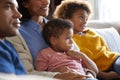 Close up of children sitting on the sofa in their living room watching TV with their parents, side view Royalty Free Stock Photo