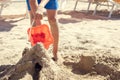 Close-up of children& x27;s hands pouring water from bucket to play with sand and build castle on beach. Royalty Free Stock Photo