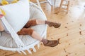 Close-up of a childs brown Brogue shoes sitting on macrame chair swing. Rustic style in the interior