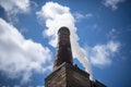 close-up of chimney, with smoke billowing out, against bright blue sky