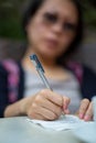 Close-up of a Chines woman writing a letter on a table.