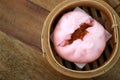 Close up Chinese steamed red pork bun is break can see pork inside in bamboo basket on wood table background Royalty Free Stock Photo