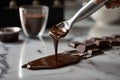 close-up of chocolate being poured over marble countertop, with metal spatulas in the background