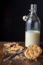 Close-up of chocolate chip cookies, crumbs, spoon and bottle with milk on wooden table, black background Royalty Free Stock Photo