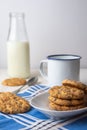 Close-up of chocolate chip cookies on white plate with cup, spoon and bottle of milk on blue napkin, with selective focus, white b Royalty Free Stock Photo