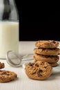 Close-up of chocolate cookies in white plate and bottle with milk, on white table, black background, Royalty Free Stock Photo