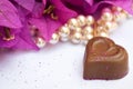 Valentines close-up of a chocolate heart with pink flowers and pearls