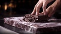 A close-up of a chocolatier's hand gently spreading Couverture Chocolate onto a marble slab