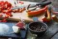 Close-up of chopped hot chili peppers and heaps of salt, sugar, garlic, allspice, bay leaf on an old wooden surface, selective