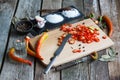 Close-up of chopped hot chili peppers and heaps of salt, sugar, garlic, allspice, bay leaf on an old wooden surface, selective