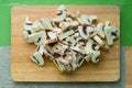 Close-up of chopped mushrooms lying on a wooden cutting board on a green kitchen table. Royalty Free Stock Photo