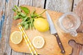 Close-up. Chopping cutting board, sliced lemon, jar, mint leaves, knife and straw on wooden table. Cocktail preparation Royalty Free Stock Photo