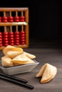 Close-up of chopsticks, fortune cookies on saucer, on dark wooden table with abacus, selective focus, black background, Royalty Free Stock Photo