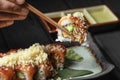 close up of chopsticks in men hands taking portion of sushi roll on the table restaurant eating sushi roll using chopsticks.