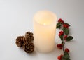 Close-up of a christmas candle lit in white background. Detail of Xmas centerpiece. Flame of white wax Royalty Free Stock Photo