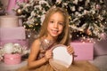 Close up. Christmas concept. A beautiful little girl in an elegant dress sits and smiles while holding a pink gift box Royalty Free Stock Photo