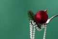 Close up of Christmas decorations on fork of white beads, branch of Christmas tree and a red Christmas ball on green Royalty Free Stock Photo